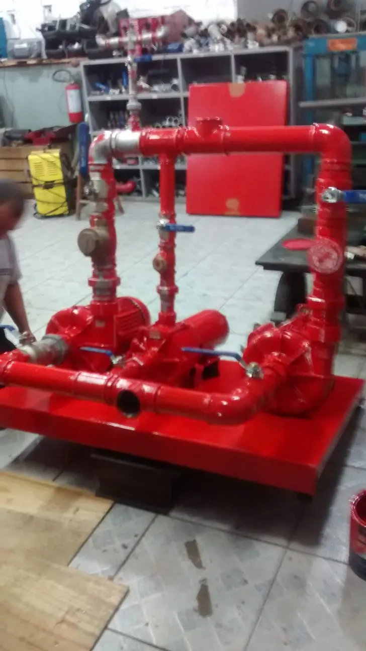 Casa de bombas com conjunto motor-bomba vermelho, barrilete e registros instalados sobre base metálica