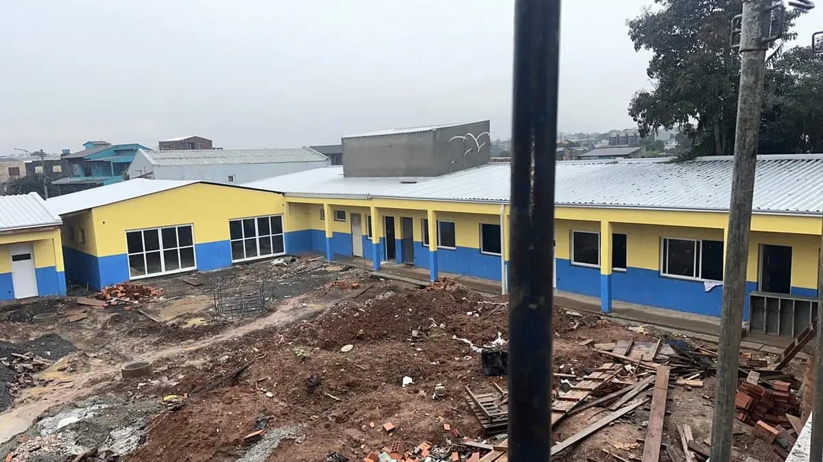 Pátio em obra, com solo revolvido, entulho e a edificação ainda sem cobertura